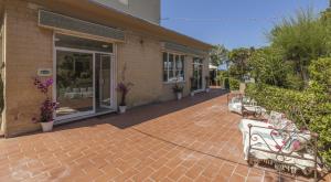 un patio en briques avec deux bancs devant un magasin dans l'établissement Hotel Quisisana, à Vada