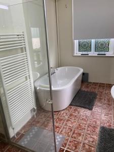 een badkamer met een bad en een glazen douche bij Sol y Mar in Vlissingen