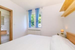 ein weißes Schlafzimmer mit einem Bett und einem Fenster in der Unterkunft Sun in Mali Lošinj