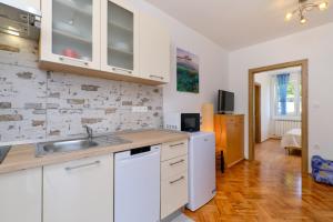 eine Küche mit weißen Schränken und einer Spüle in der Unterkunft Sun in Mali Lošinj + 13 Fotos