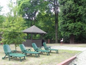 a group of green lawn chairs and a gazebo at Dom Wczasowy Magnolia in Lądek-Zdrój