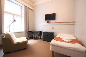 um quarto com uma cama, uma cadeira e uma televisão em Forenom Hostel Röykkä em Helsínquia