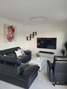 ein Wohnzimmer mit schwarzen Ledermöbeln und einem Flachbild-TV in der Unterkunft Dragovoda bay in Ubli