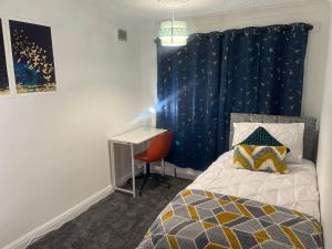 a bedroom with a bed with a blue curtain and a desk at The Leckhampton - Company and Family Stays Chester Road in Walsall