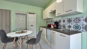 a kitchen with a sink and a table and chairs at Gardencity Apartmanház in Győr