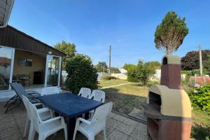 a patio with a blue table and white chairs at Elma Stay Location LEstran in Marennes