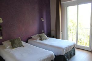 2 bedden in een hotelkamer met een raam bij Les Bruyeres in Plélan-le-Grand