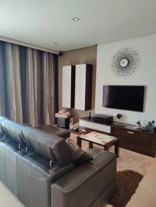 a living room with a leather couch and a flat screen tv at Luxury Seaview Mellieha Apartment in Mellieħa