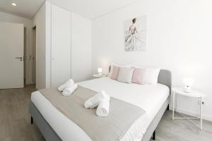 Un dormitorio blanco con una cama grande con toallas. en Blissful Beach Getaway en Nazaré