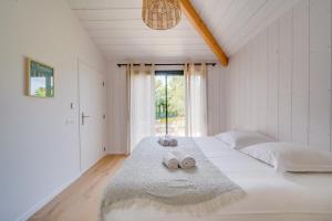 1 dormitorio con 1 cama blanca grande y toallas. en Villa Tchanquée, en Gujan-Mestras