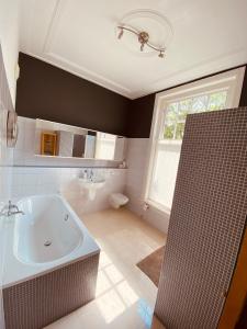 een badkamer met een bad, een wastafel en een raam bij Bed and Breakfast Juliana in Eindhoven