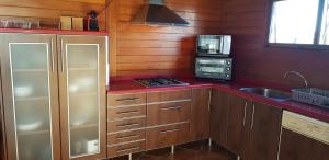 a kitchen with wooden cabinets and a sink and a microwave at LA TRAMUNTANA CULLERA Playa Marenyet a 300 metros in Valencia