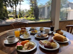 a wooden table with plates of breakfast food on it at Pousada Granja Santa Barbara in Petrópolis