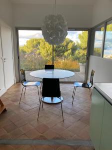 une table et des chaises dans une chambre avec une grande fenêtre dans l'établissement Sète, Belle maison dans la pinède - piscine et vue, à Sète