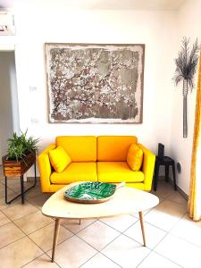 a yellow couch in a living room with a table at Il Melograno Apartment (Centro Storico Prato) in Prato