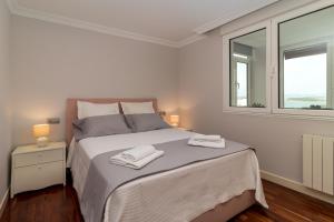 a white bedroom with a bed with two towels on it at El Balcón de Charles in Santander