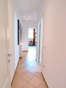 un corridoio con pareti bianche e pavimento piastrellato di Il Melograno Apartment (Centro Storico Prato) a Prato