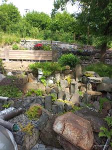 un jardín con un banco y algunas rocas en Apartmán Dobrná, 