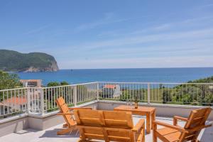 a balcony with two chairs and a table and the ocean at Apartments Bonazza in Petrovac na Moru