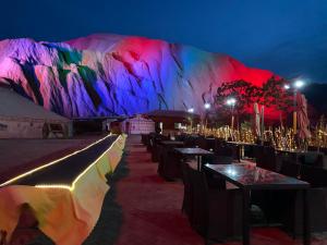 a group of tables and chairs with a mountain at night at KaoShan Tent Zhangye in Zhangye