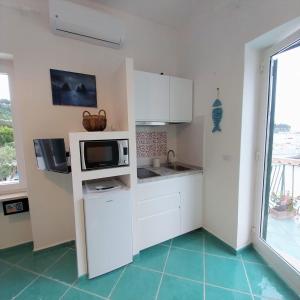 a kitchen with white cabinets and a microwave at Villa del Sole in Capri