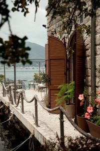 un edificio con una porta in legno e alcuni fiori di Carrubba a Tivat