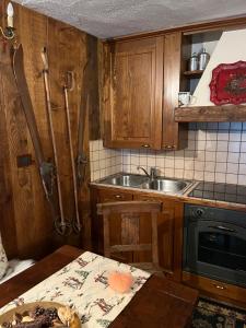 a kitchen with wooden cabinets and a sink and a table at Cozy Apartment Ruitor in La Thuile +11 photos