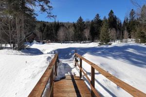 un paseo marítimo de madera en la nieve con una valla en La Rikiki du petit ruisseau, en Mandeville
