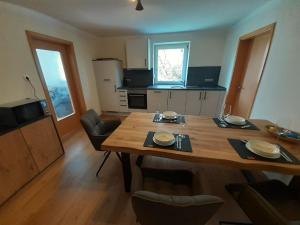 eine Küche mit einem Holztisch mit Stühlen und einem Esszimmer in der Unterkunft Ferienwohnung Kreiller in Johanniskirchen