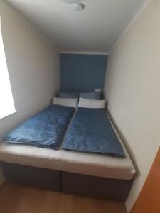 ein kleines Bett in einem kleinen Zimmer mit blauen Wänden in der Unterkunft Ferienwohnung Kreiller in Johanniskirchen