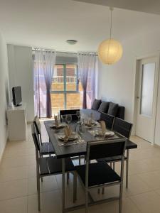 - une salle à manger avec une table, des chaises et un canapé dans l'établissement Apartamento VI-DA SOL, à Puerto de Sagunto