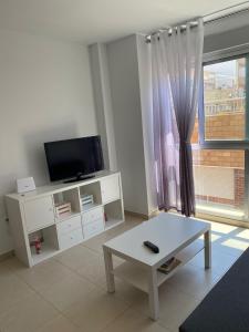 a living room with a tv and a table and a window at Apartamento VI-DA SOL in Puerto de Sagunto
