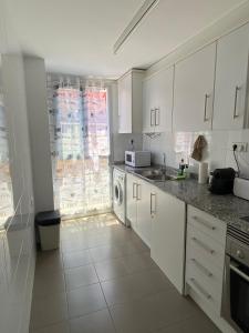 - une cuisine avec des placards blancs et un lave-linge/sèche-linge dans l'établissement Apartamento VI-DA SOL, à Puerto de Sagunto