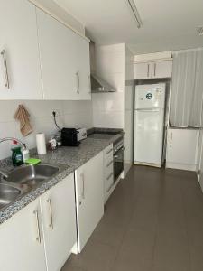 a white kitchen with a sink and a refrigerator at Apartamento VI-DA SOL in Puerto de Sagunto