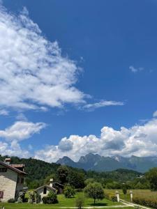 um céu azul com nuvens e montanhas ao fundo em Fienile Chiaramada em Belluno