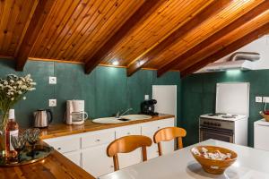 a kitchen with green walls and wooden ceilings at Attico Verde in Kastanéa