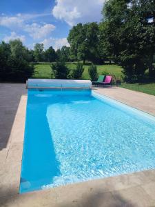 een zwembad met blauw water in een tuin bij Le Grenier - Chambre d'hôtes 