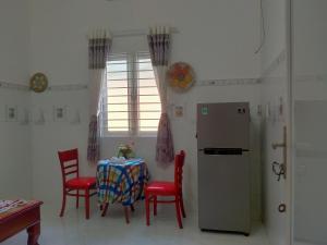 a kitchen with a table with red chairs and a refrigerator at Room in Vietnam 1 in Ben Tre