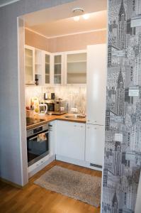 een keuken met witte kasten en stadsbehang bij Aleksandria Apartment in Pärnu