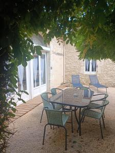 un patio con mesa y sillas bajo un árbol en Gite Chambre Naomie, en Parranquet