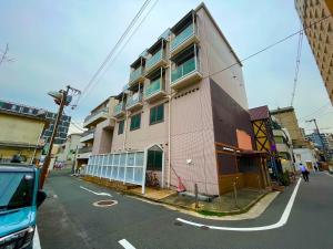 ein rosafarbenes Gebäude an der Straßenseite in der Unterkunft 東横のヨコ in Okayama