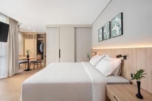 Un dormitorio con una gran cama blanca y una mesa en Address São Paulo Faria Lima by Intercity, en São Paulo