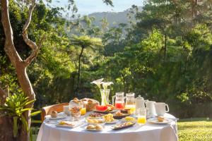 una mesa blanca con comida y bebidas. en Pousada Tijupá, en Visconde De Maua