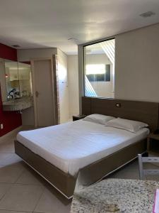 1 dormitorio con 1 cama grande y ventana grande en Motel Kalipso en São José