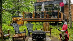 un patio trasero con sillas y una casa con terraza en The Marco-Polo of Portneuf - Open on nature - Private SPA Pool Sauna, en Pont-Rouge