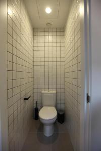 a bathroom with a toilet in a white tiled wall at AZ The Botanic Hostel in Zaragoza