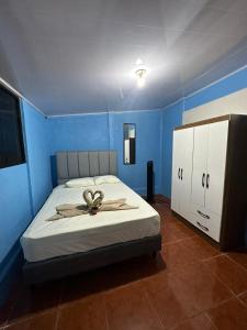a bedroom with a bed and a blue wall at La Casa de Detours Costa Rica in Fortuna