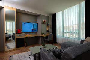 a living room with a couch and a desk with a television at Brand Business Hotel in Corlu