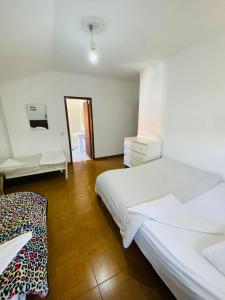 a white bedroom with a bed and a desk at Come Inn Sesimbra in Quinta do Conde
