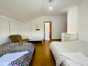 a room with two beds and a chair in it at Come Inn Sesimbra in Quinta do Conde